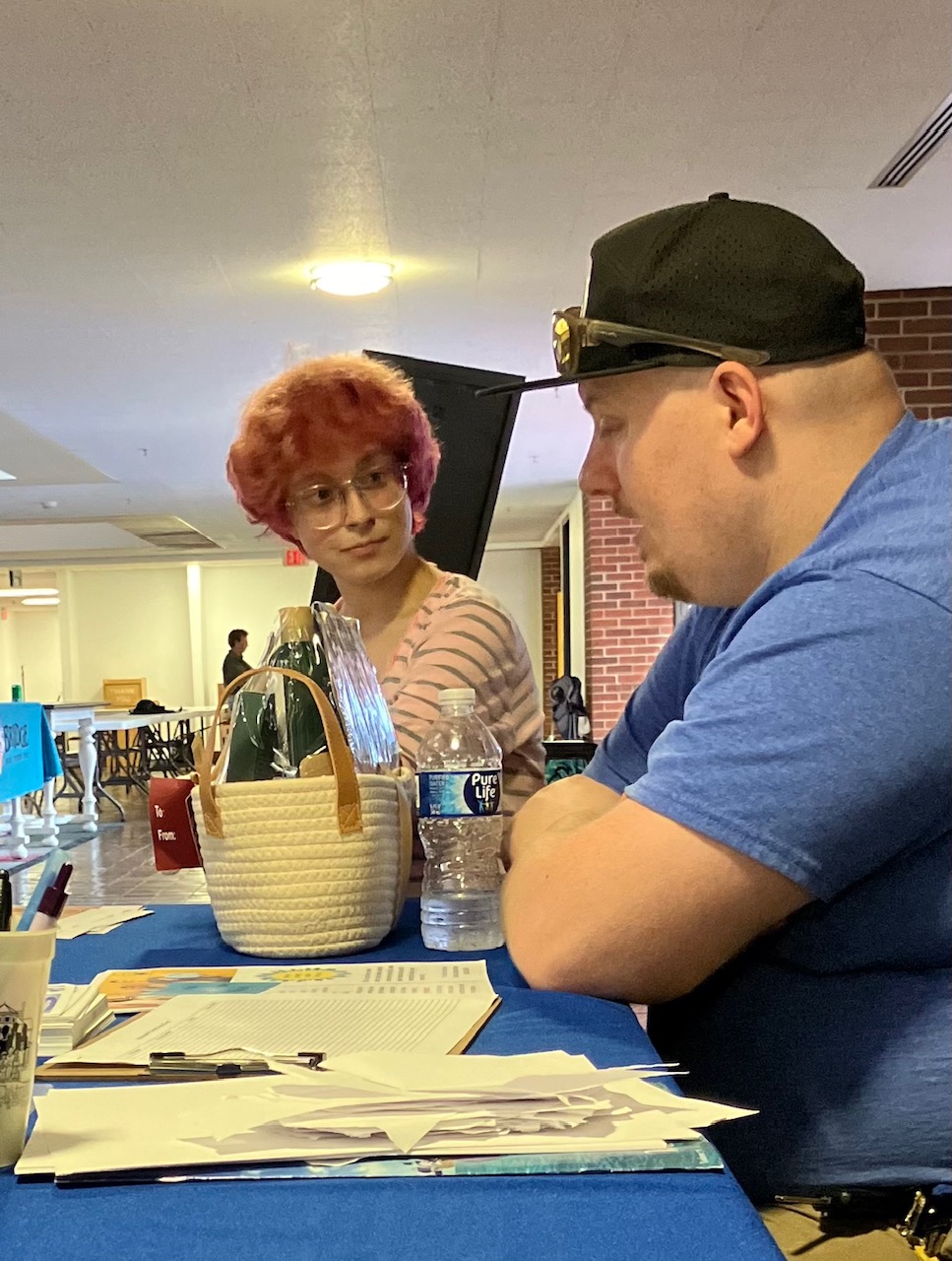 A community member speaking with housing support staff at an expo table